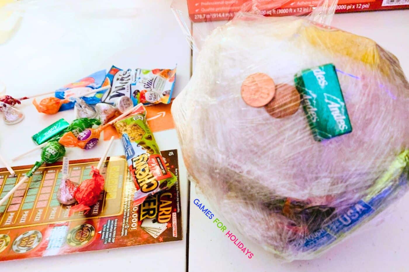 how to make the Saran Wrap Christmas - plastic wrap ball and Christmas game prizes on a table for Christmas party games